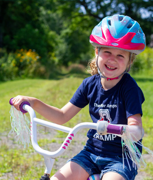 Vanessa, a young left arm amputee, wears a prosthetic arm with an attachment to hold onto the handlebars of her bike.