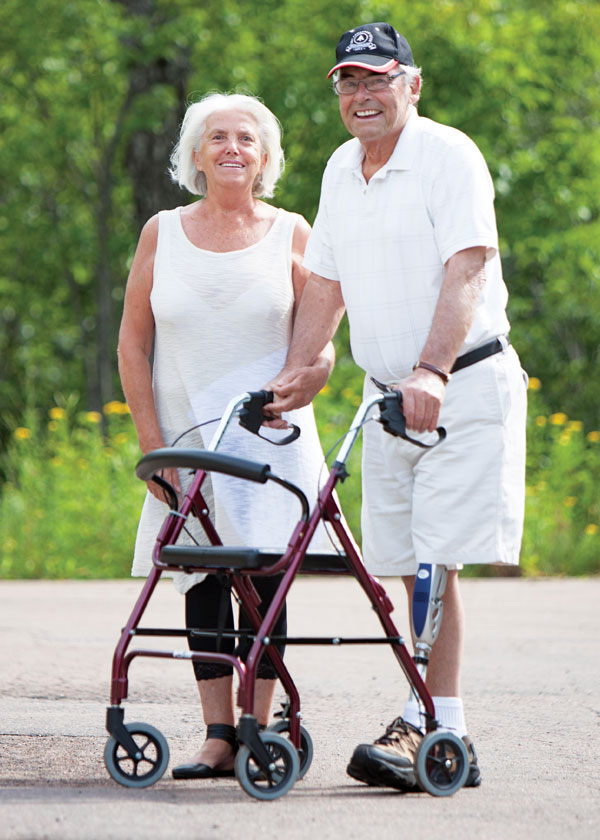 A senior male leg amputee stands beside his wife outside.