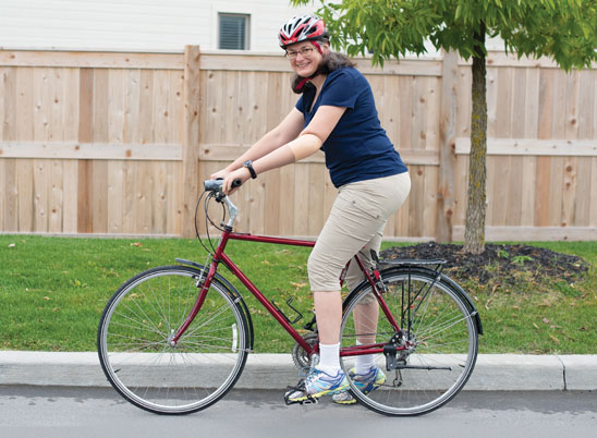 An adult arm amputee rides her bike down a street.