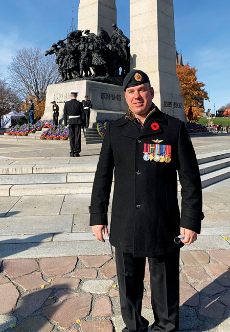 An adult male war amputee veteran stands in front of the National War Memorial on Remembrance Day.