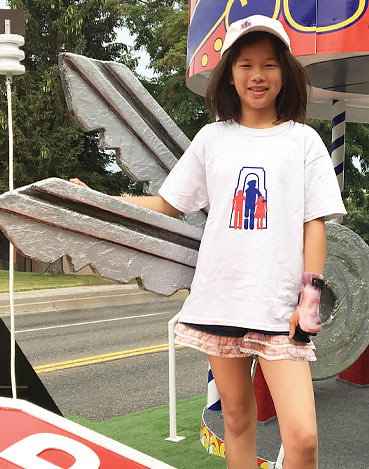 A child amputee standing on The War Amps PLAYSAFE/DRIVESAFE float during a parade.