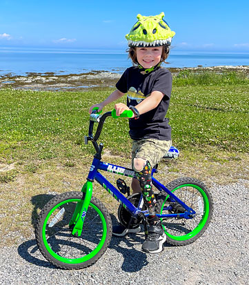 Un garçon ayant plusieurs amputations fait du vélo près de l’océan.