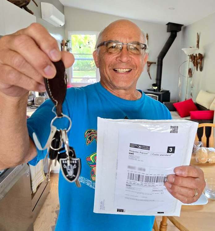 Un homme plus âgé tient un trousseau de clés et une enveloppe de messageries.