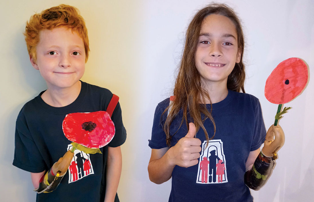 A young male arm amputee holds the poppy he made during a virtual poppy-making event. A young male arm amputee gives a thumbs-up and holds the poppy he made during a virtual poppy-making event.