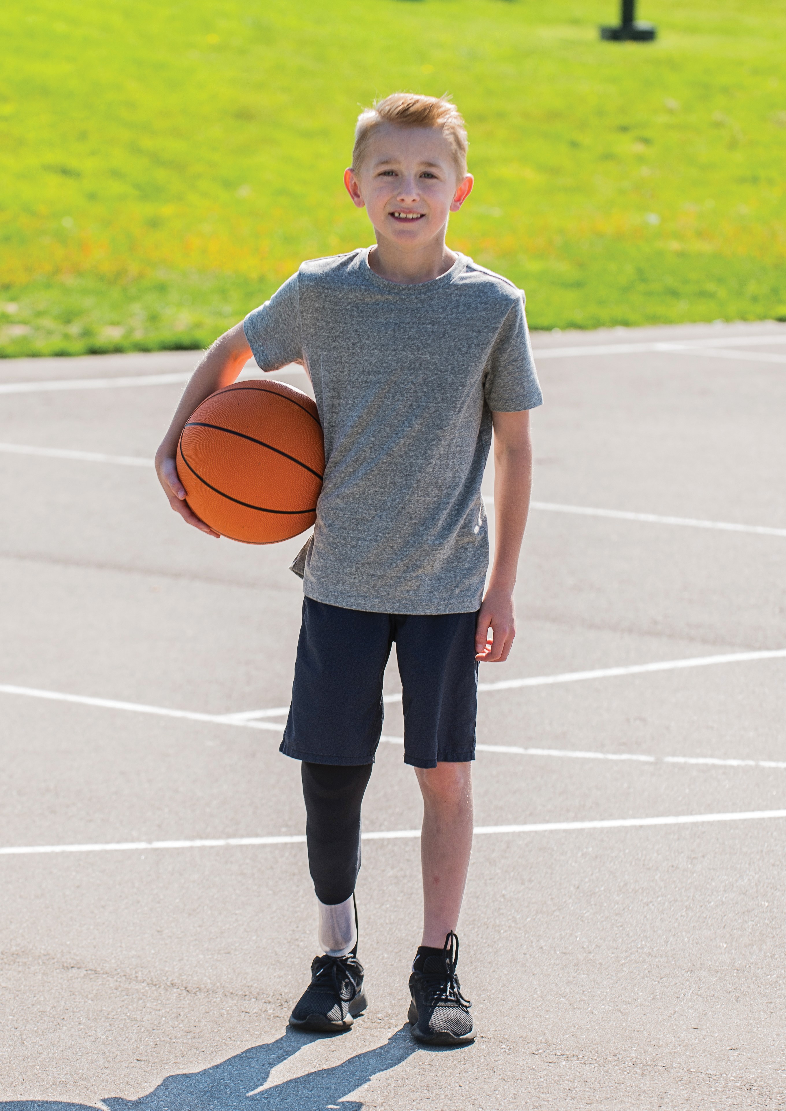 Cooper, a leg amputee, holding a basketball.