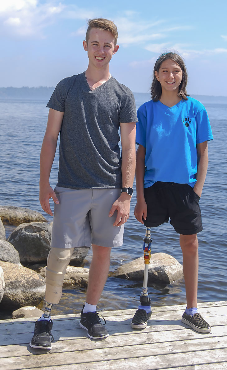 Safety Ambassadors Rebecca and Adam, both leg amputees, standing on a dock by a lake.
