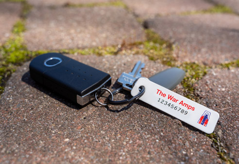 A set of keys with a War Amps key tag attached lying on the ground.