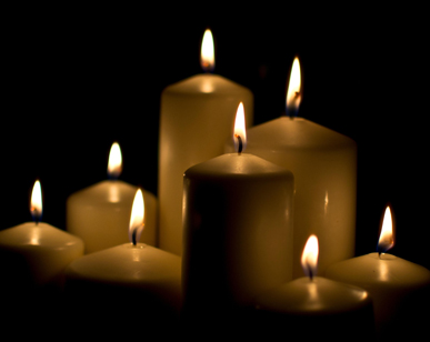 Eight white candles of varying heights burning softly.